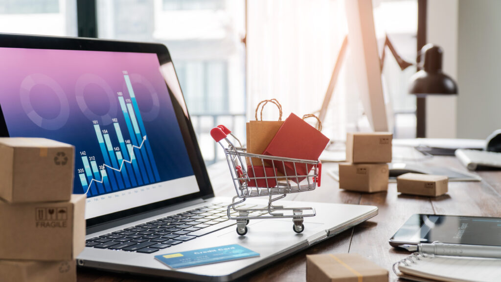 trolley full of shopping bags on a laptop with crredit card to represent e-commerce and the emv 3ds update