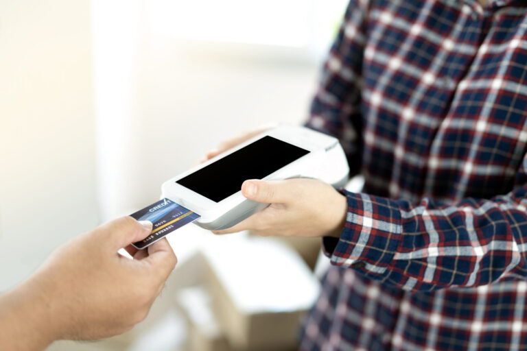 Close-up of entrepreneur using EDC to receive credit card for payment from customer in her store.