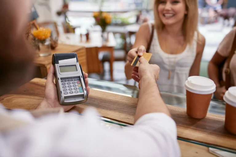 woman handing over her card for payment on a pay as you go card machine