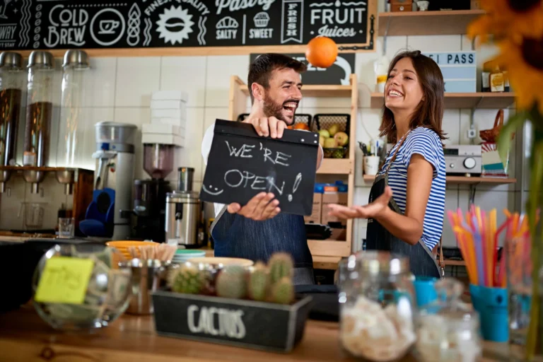 small local business staff holding a we're open sign in cafe