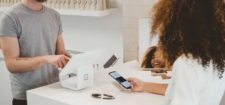 woman paying business on e wallet on phone through a card machine pos system