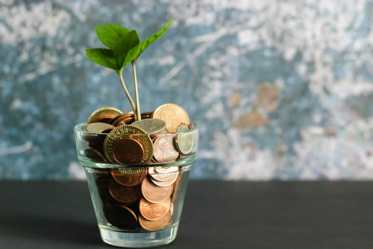 glass full of coins and plant sprouting from them to convey business growth