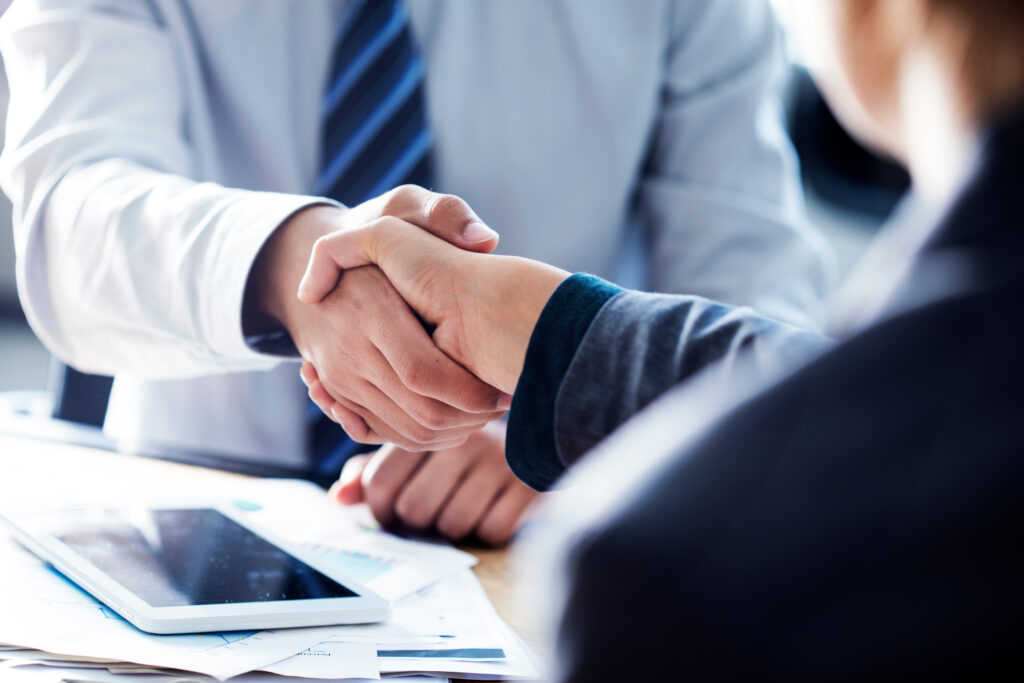 two people in suits exchanging a business handshake over a merchant service