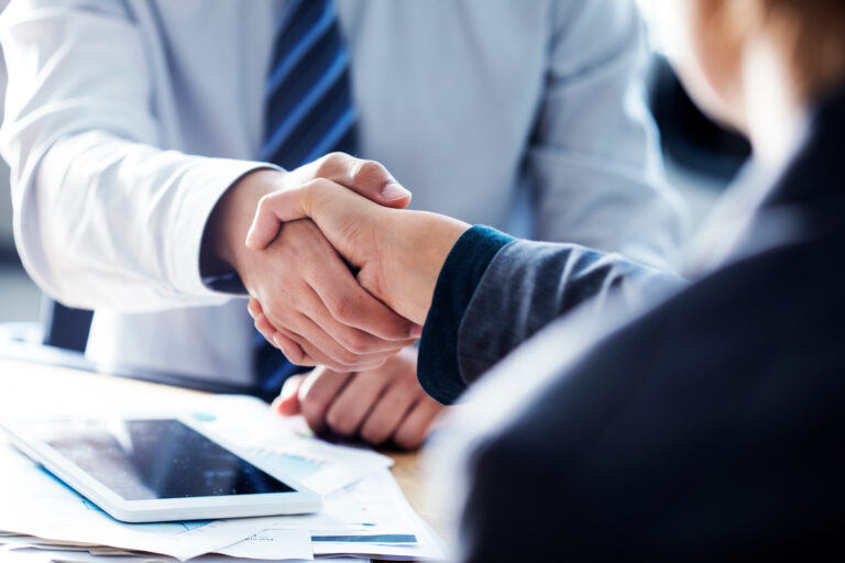 two people in suits exchanging a business handshake over a merchant service
