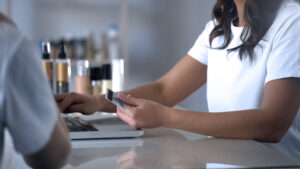 Lady paying for service of beauty salon clinic by card, femininity, comfortable banking