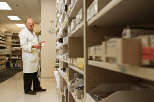 chemist taking stock in his pharmacy, medicines on shelves in pharmacies stock room