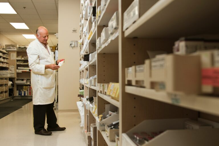 chemist taking stock in his pharmacy, medicines on shelves in pharmacies stock room