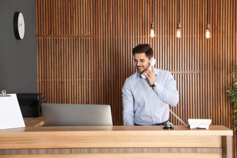 Receptionist talking on phone at desk in lobby representing virtual terminals